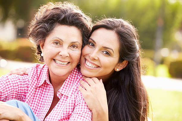 Mother With Adult Daughter In Park Together Smiling To Camera