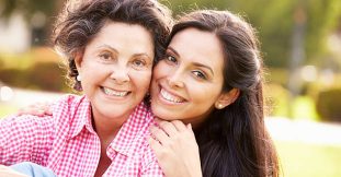 Mother With Adult Daughter In Park Together Smiling To Camera